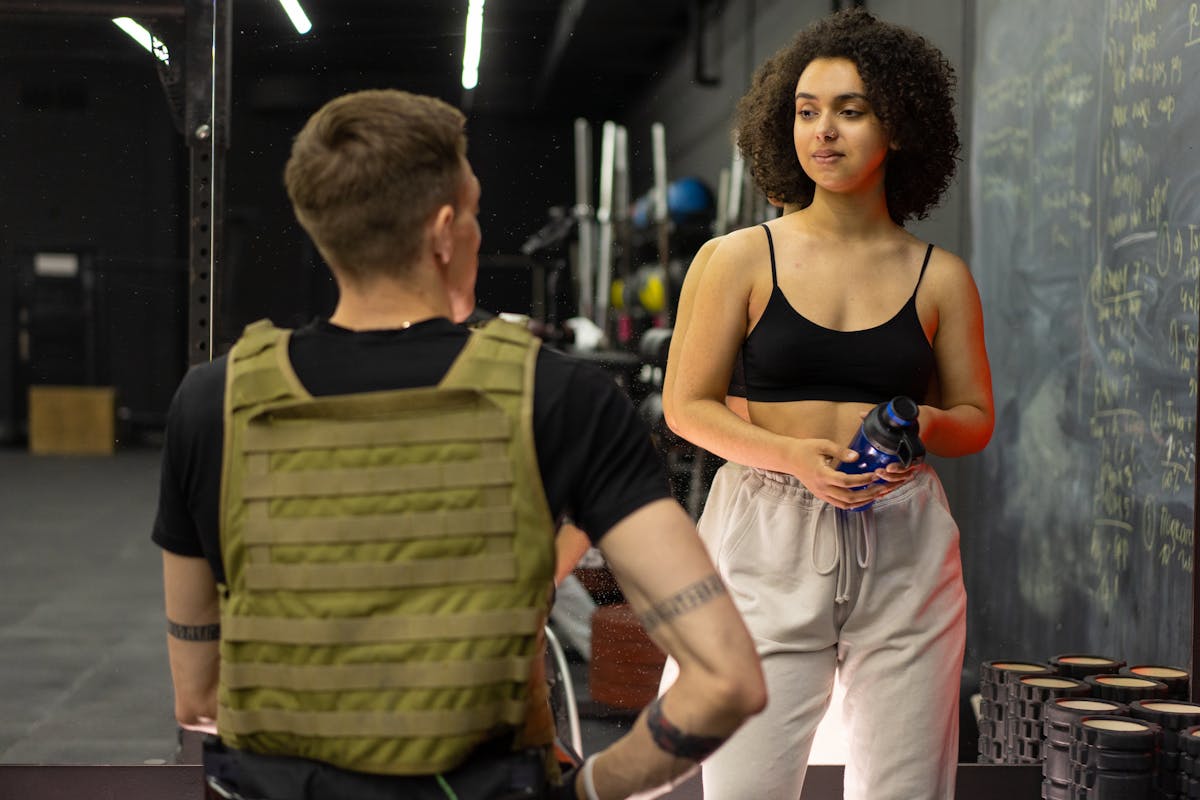 Volta de teste físico nos EUA reacende debate sobre avaliação e treino personalizado 2 Personal trainer conversa com aluna em academia durante avaliação de treino